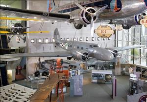 Airplanes of different sizes hang from the ceiling of a museum